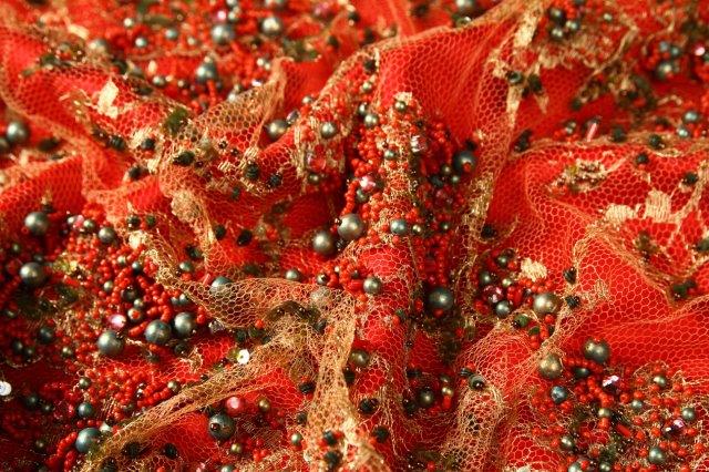 Ref 1355 tulle dore perle de perles rouges vertes presente sur fond de satin rouge